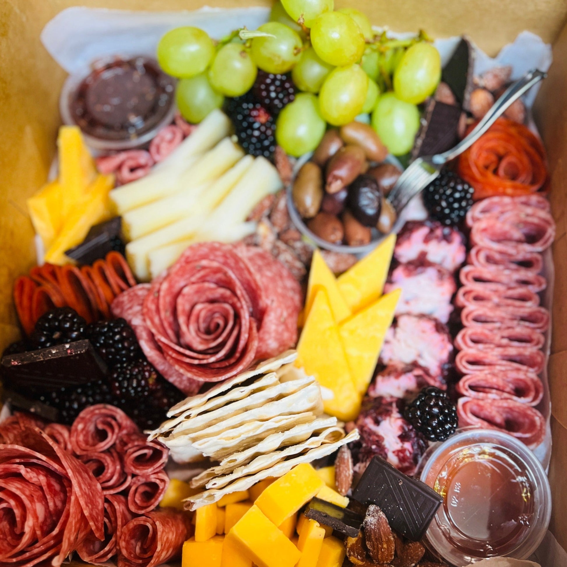 Charcuterie box with cheese, cured, meat, and fruit.